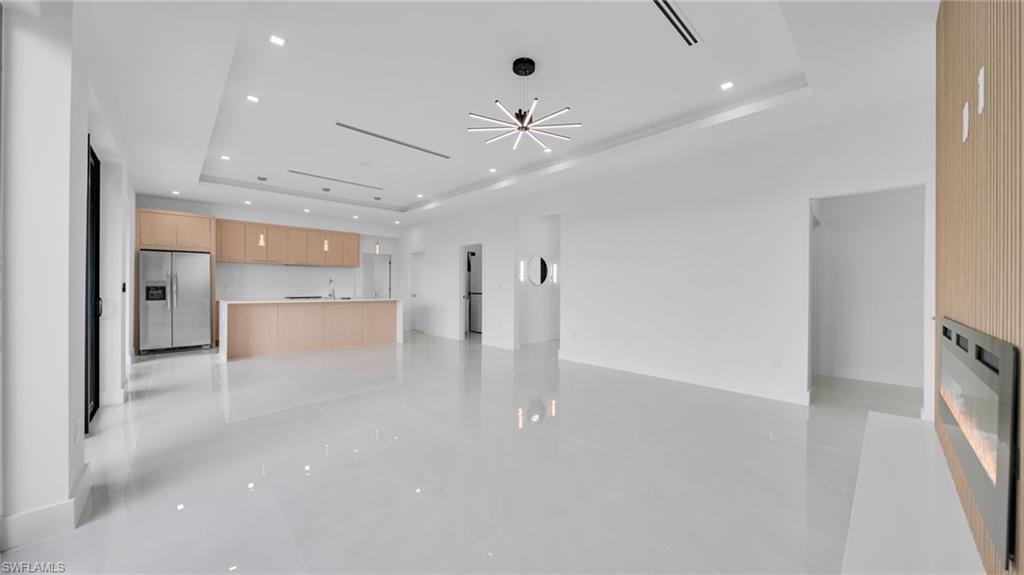 Unfurnished living room with a tray ceiling, recessed lighting, and a chandelier