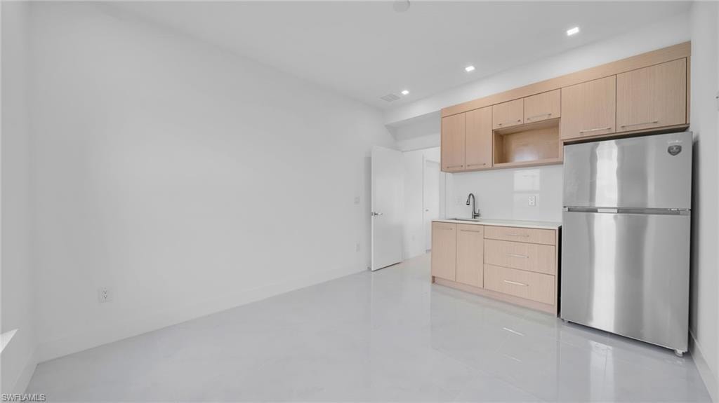 Kitchen featuring light brown cabinetry, freestanding refrigerator, light countertops, modern cabinets, and recessed lighting