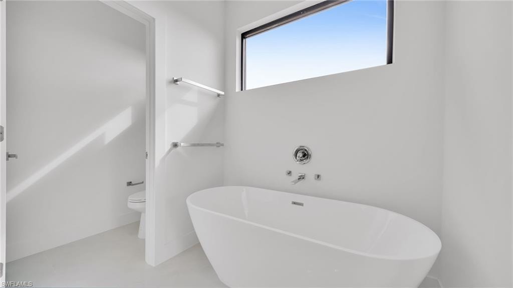 Full bath featuring a freestanding tub and toilet