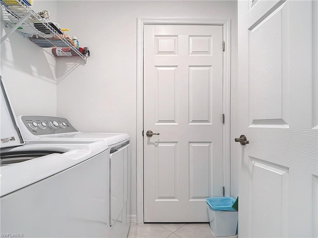 Laundry room with light tile patterned floors and washing machine and clothes dryer