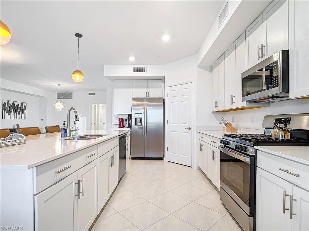Kitchen with appliances with stainless steel finishes, decorative light fixtures, white cabinetry, and sink