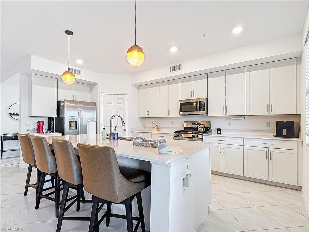 Kitchen featuring white cabinets, hanging light fixtures, sink, and appliances with stainless steel finishes