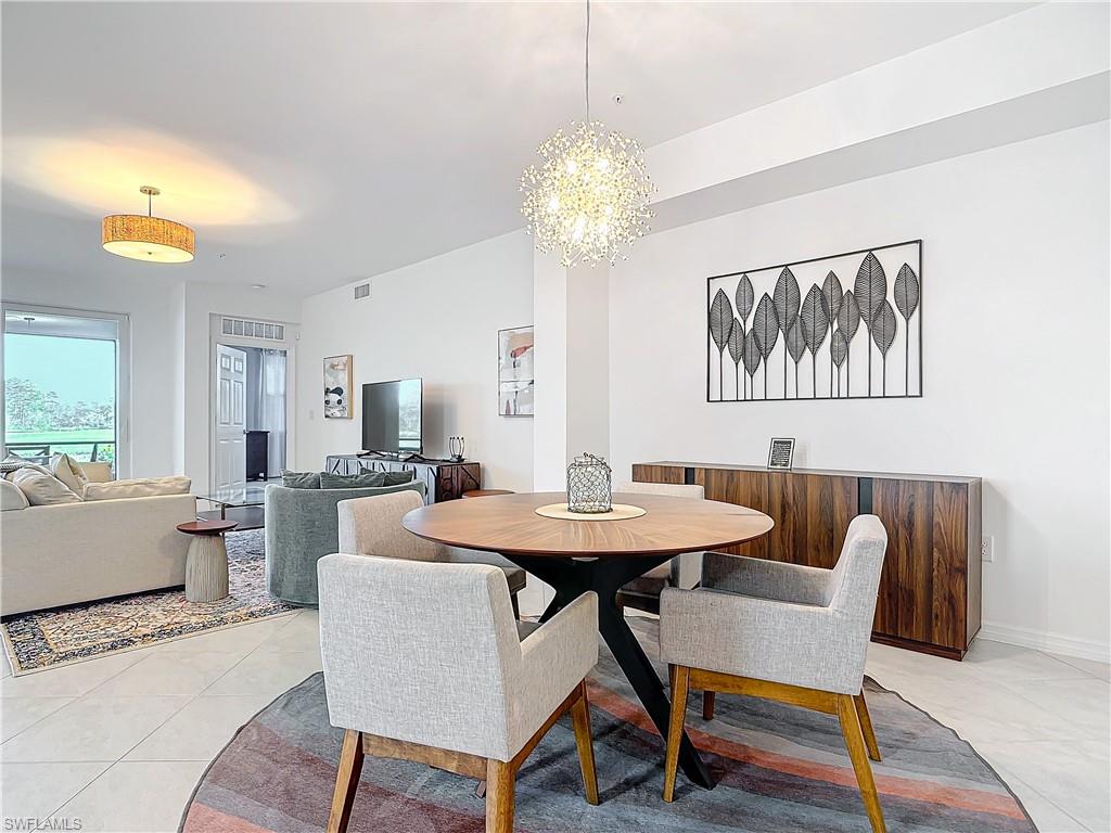Dining space with light tile patterned flooring and an inviting chandelier