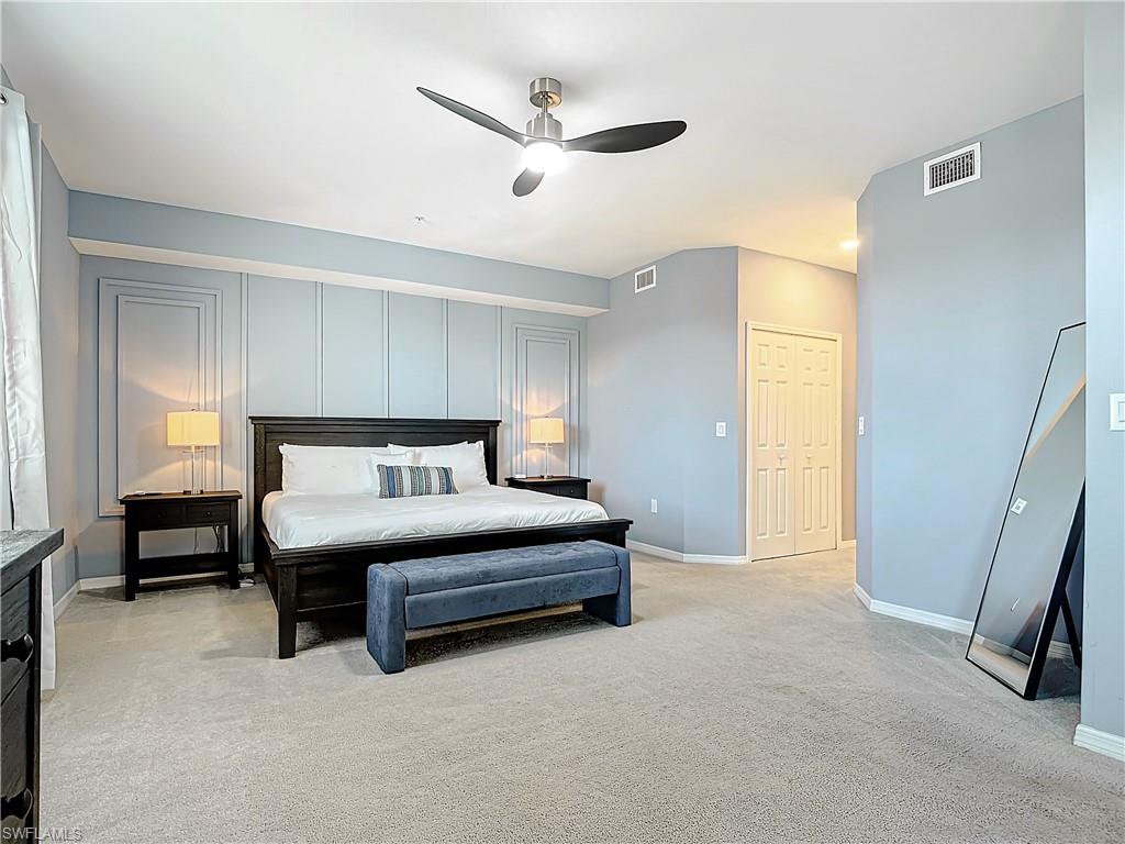 Carpeted bedroom with ceiling fan and a closet