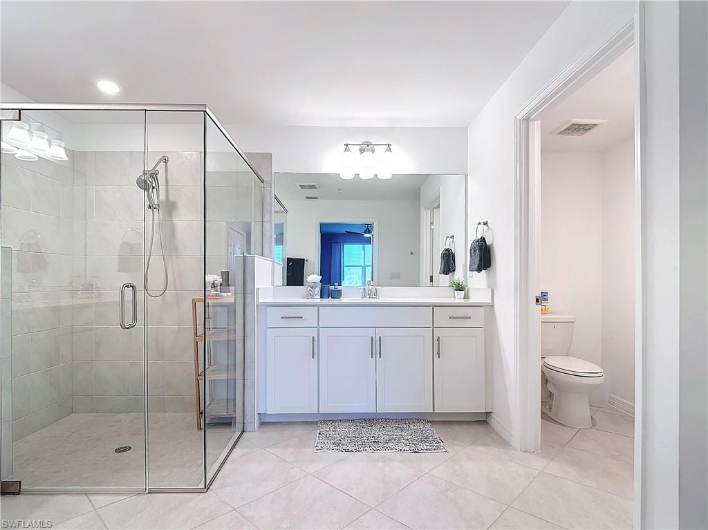 Bathroom with tile patterned flooring, vanity, toilet, and walk in shower