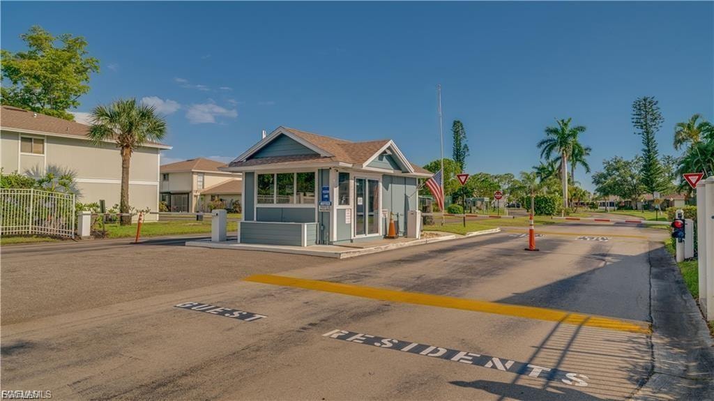 View of asphalt road with a speed bump, traffic signs, a gated entry, and curbs