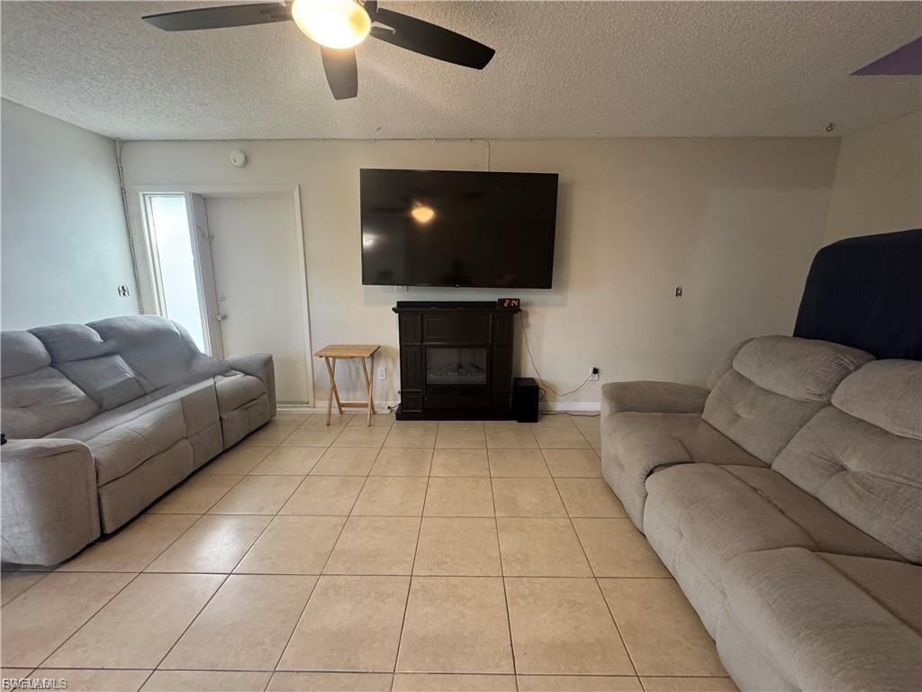Living area with a textured ceiling, a glass covered fireplace, and tile patterned floors