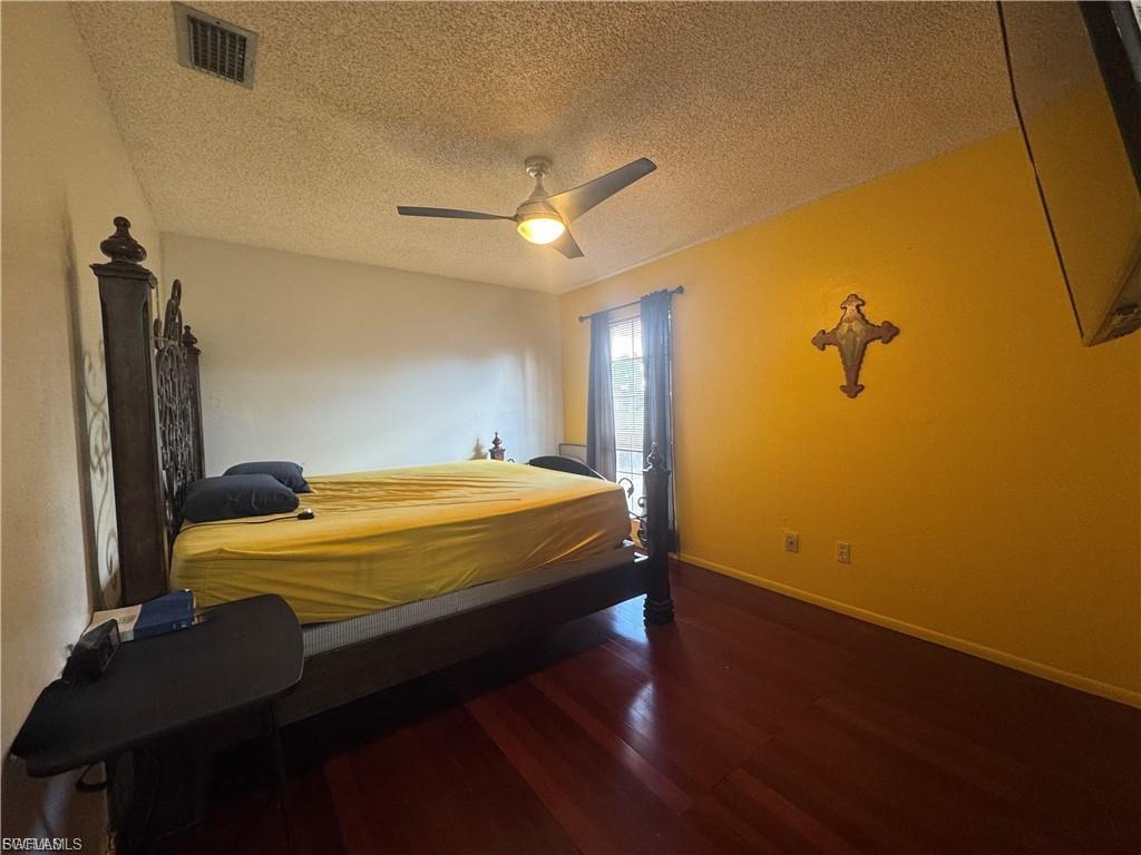 Bedroom with dark wood finished floors, a textured ceiling, and a ceiling fan