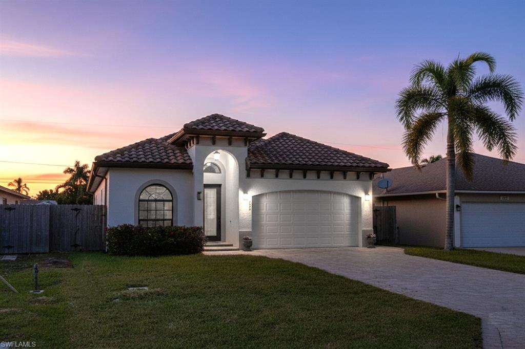 Mediterranean / spanish-style home featuring a garage, driveway, a tile roof, and stucco siding