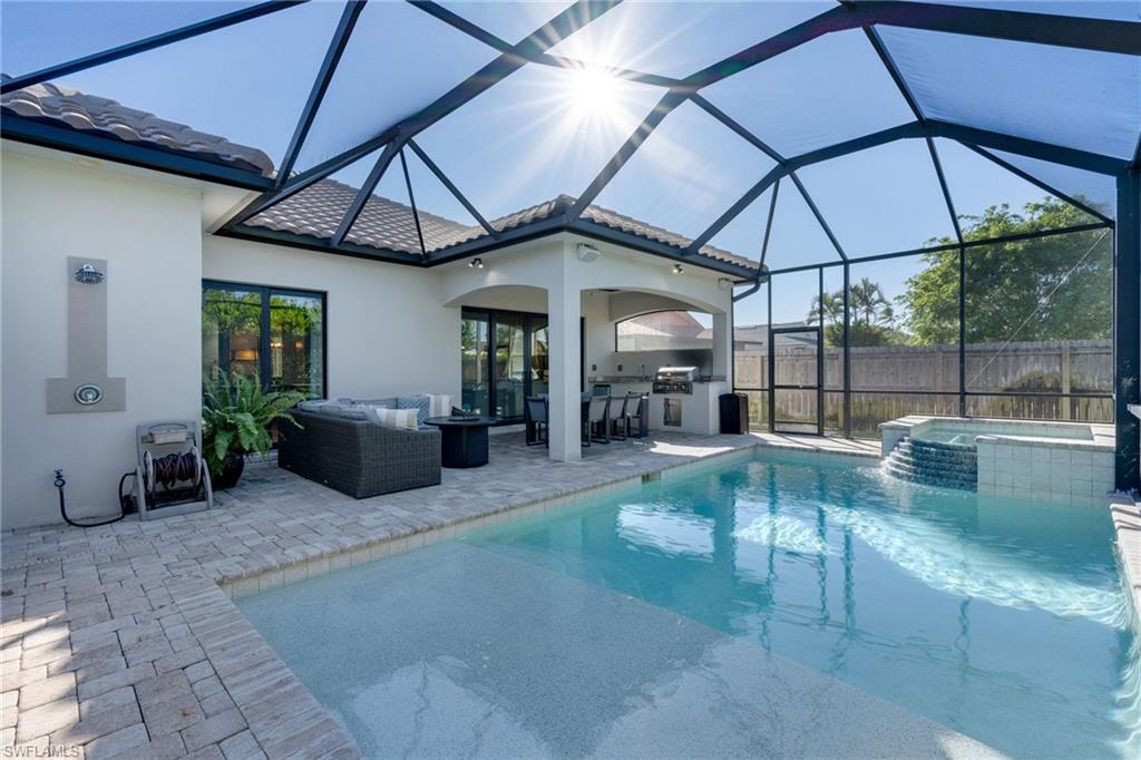 View of pool with area for grilling, a sunroom, a lanai, a patio, and a pool with connected hot tub