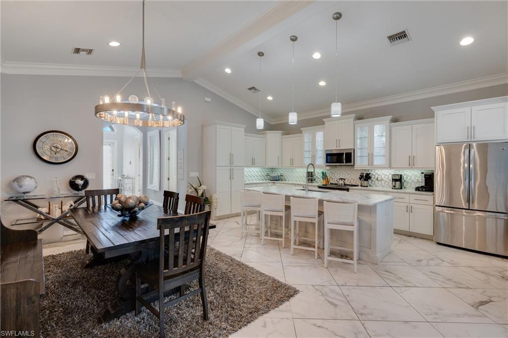 Dining room featuring ornamental molding, light marble finish flooring, and a chandelier