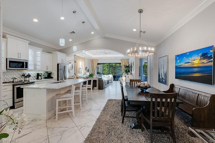 Dining area with light marble finish floors, vaulted ceiling, and ornamental molding