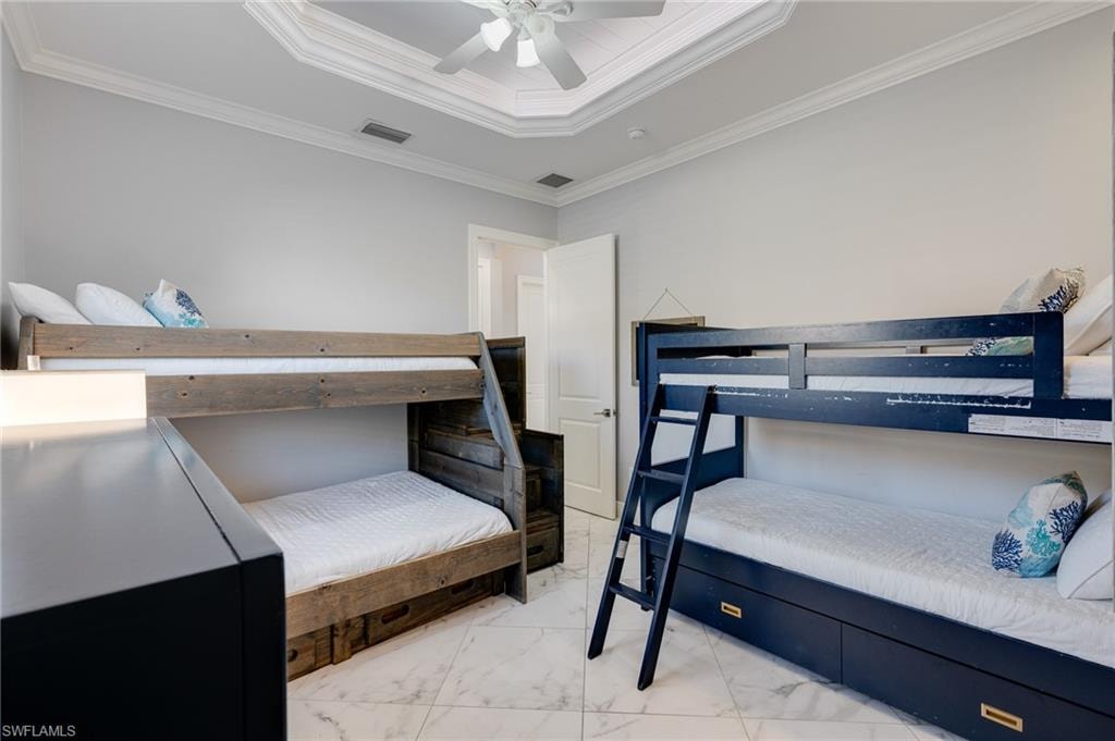 Bedroom with a tray ceiling, ornamental molding, and a ceiling fan