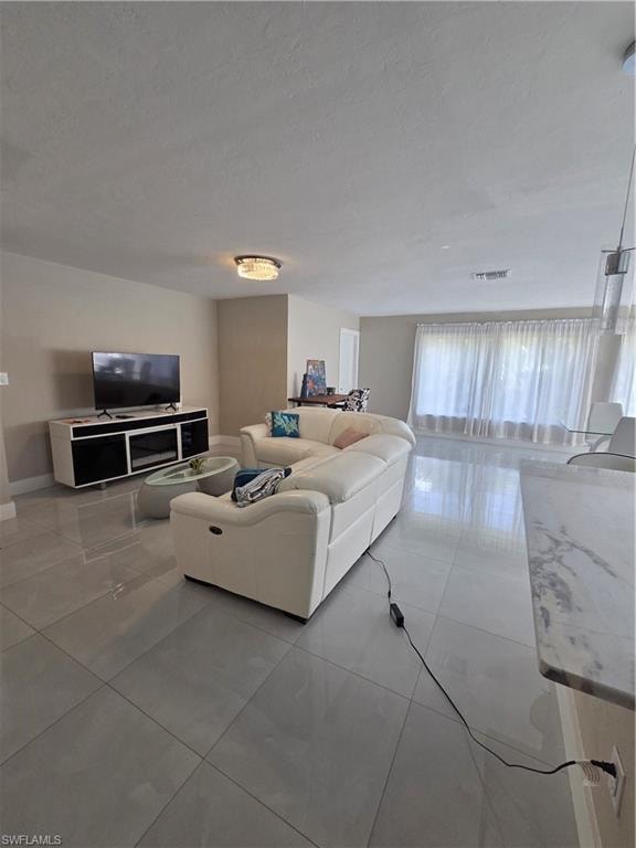 Living area with light tile patterned floors and a textured ceiling