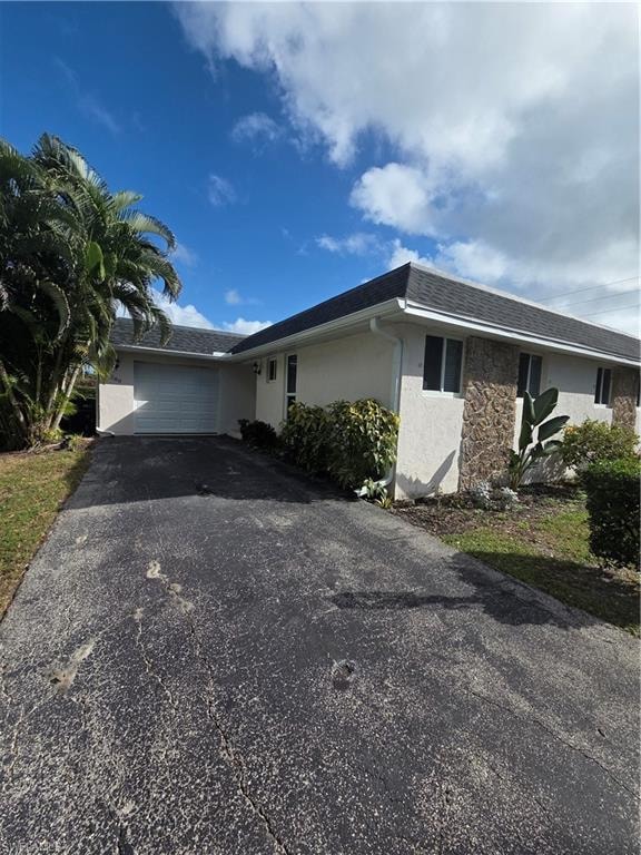 Single story home with stucco siding, a garage, asphalt driveway, and roof with shingles