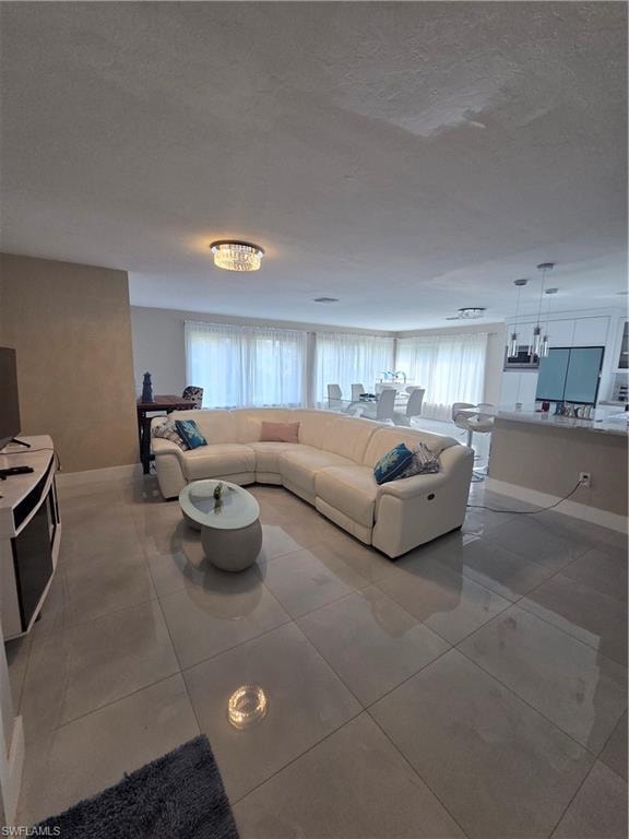 Living room with plenty of natural light, a chandelier, a textured ceiling, and light tile patterned floors