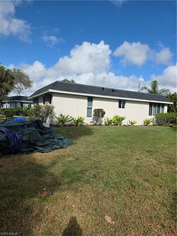 Rear view of house with a lawn and stucco siding