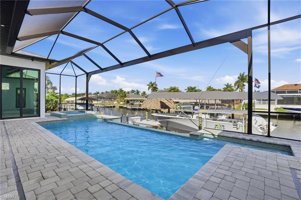 View of swimming pool featuring a sunroom, a lanai, a water view, a patio, and boat lift