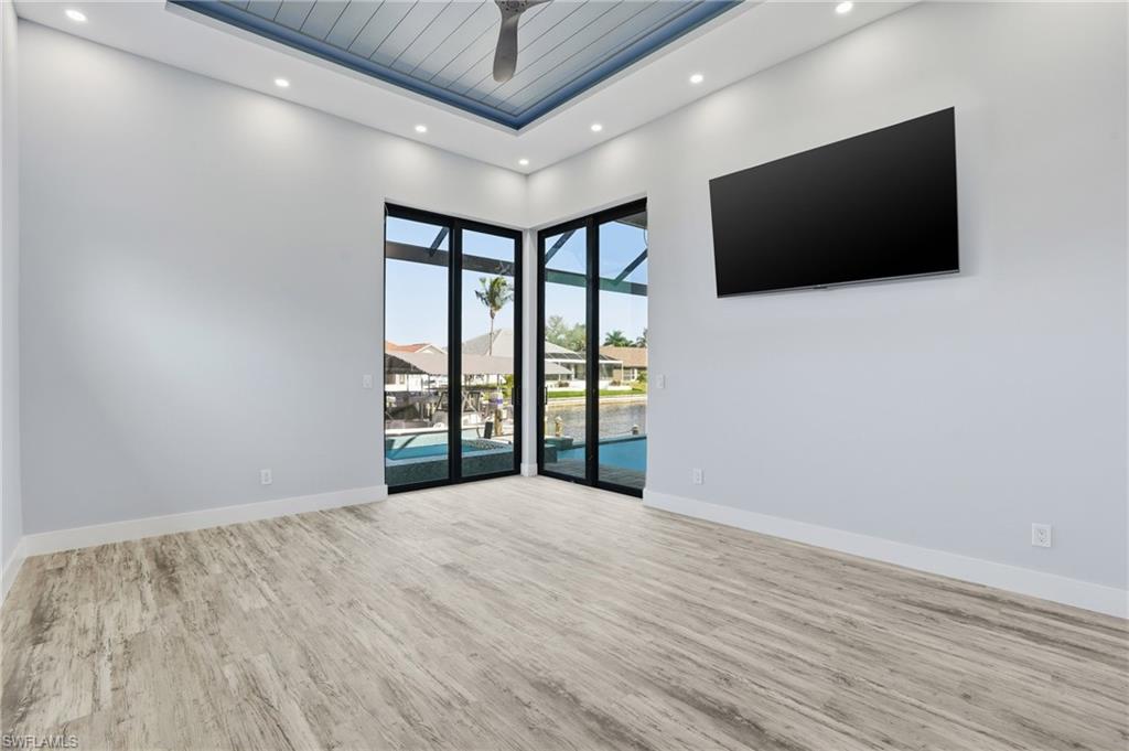 Spare room featuring a high ceiling, a sunroom, wood finished floors, recessed lighting, and ceiling fan