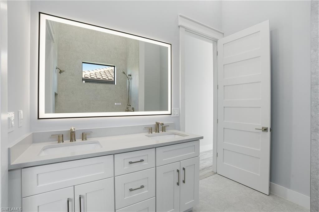 Full bath with tiled shower and double vanity
