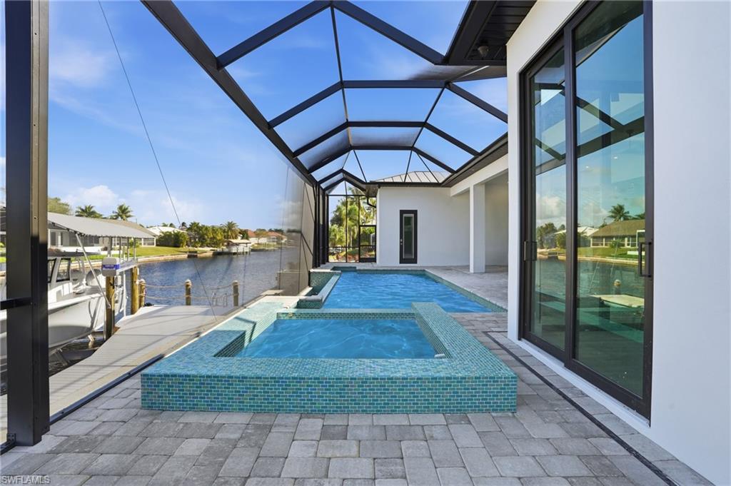 Swimming pool with an in-ground hot tub, a patio area, a sunroom, a water view, and a lanai