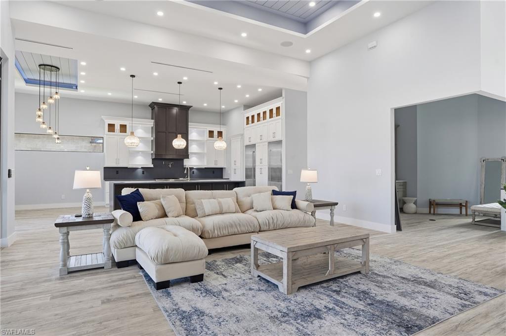 Living area with light wood-style floors, recessed lighting, a high ceiling, and a tray ceiling