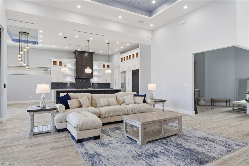 Living area with light wood finished floors, recessed lighting, a towering ceiling, and a raised ceiling