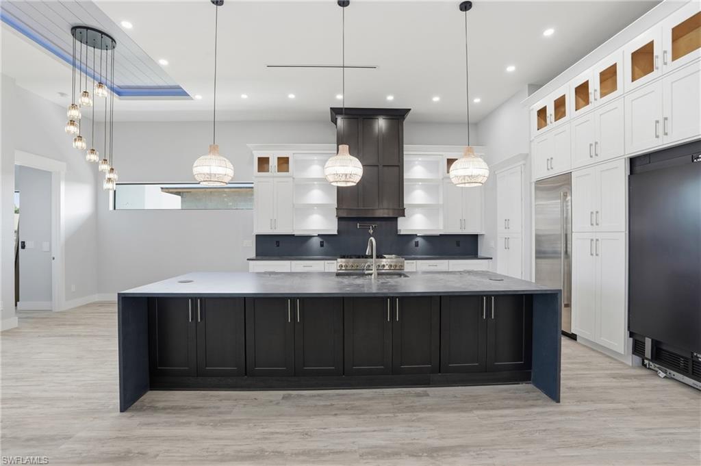 Kitchen with glass insert cabinets, white cabinetry, dark cabinetry, pendant lighting, and recessed lighting