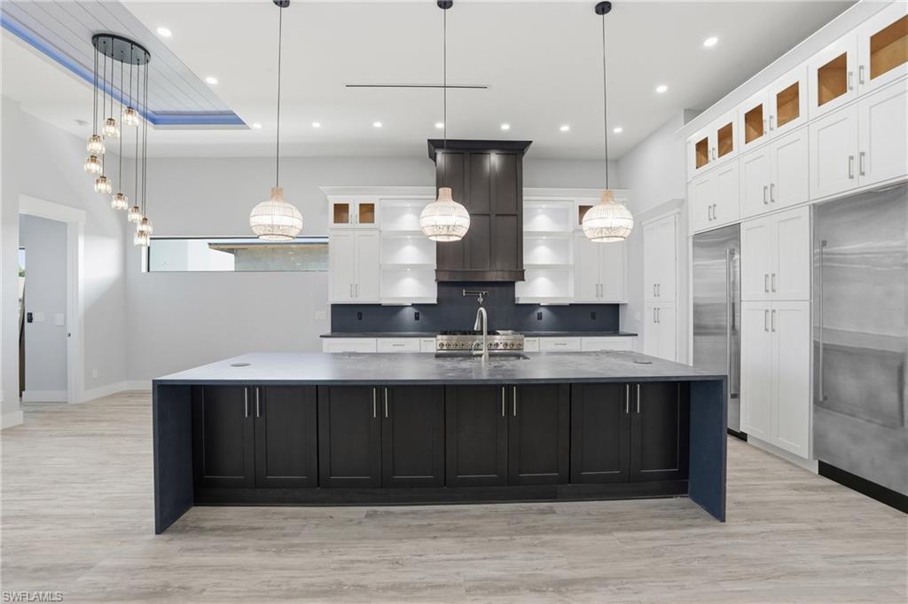 Kitchen featuring glass insert cabinets, white cabinets, dark cabinets, pendant lighting, and recessed lighting