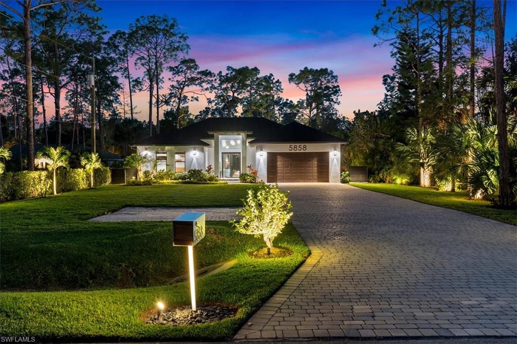 View of front of home featuring a garage, a front yard, stucco siding, and decorative driveway
