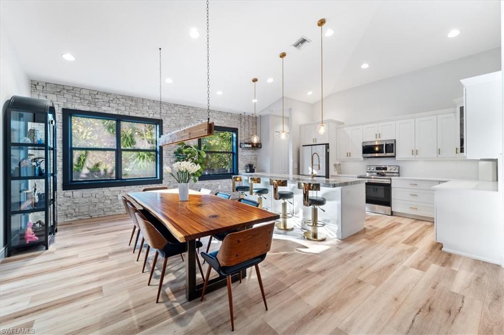 Dining space with recessed lighting, light wood finished floors, visible vents, and a high ceiling