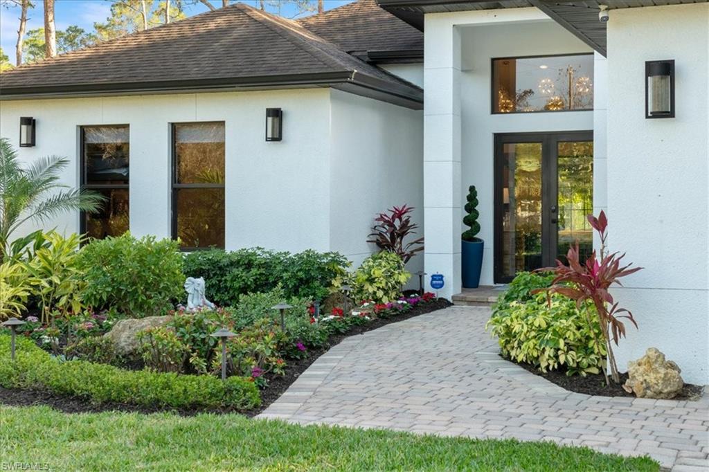 View of exterior entry with roof with shingles and stucco siding
