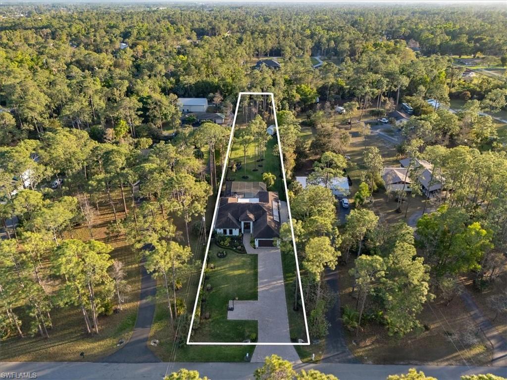 Aerial perspective of suburban area featuring property parcel outlined and a heavily wooded area