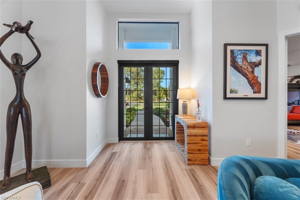 Foyer with light wood-style floors, french doors, and a high ceiling