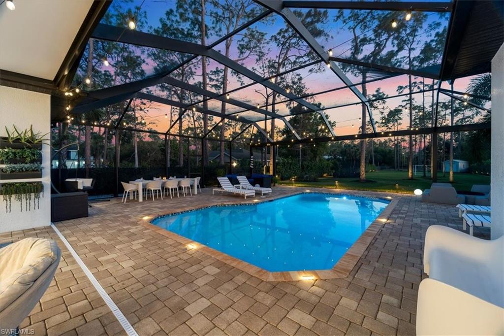 Pool at dusk with an outdoor pool, a patio, and a lanai