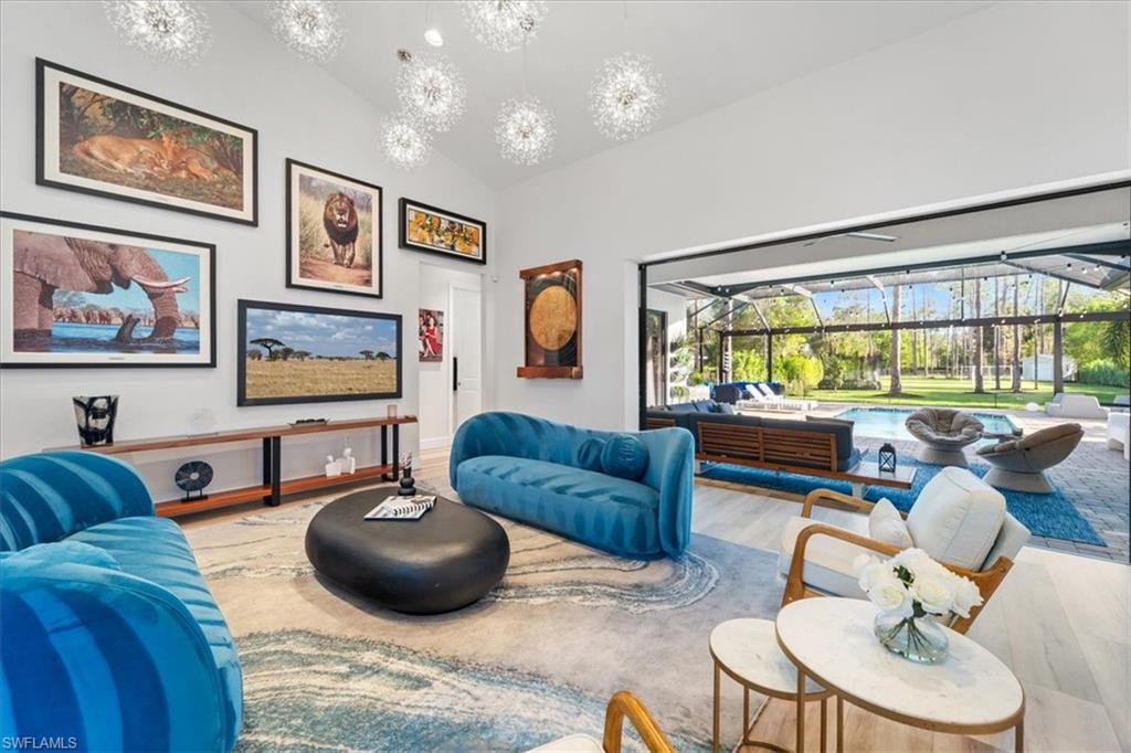 Living area featuring high vaulted ceiling, a notable chandelier, and wood finished floors