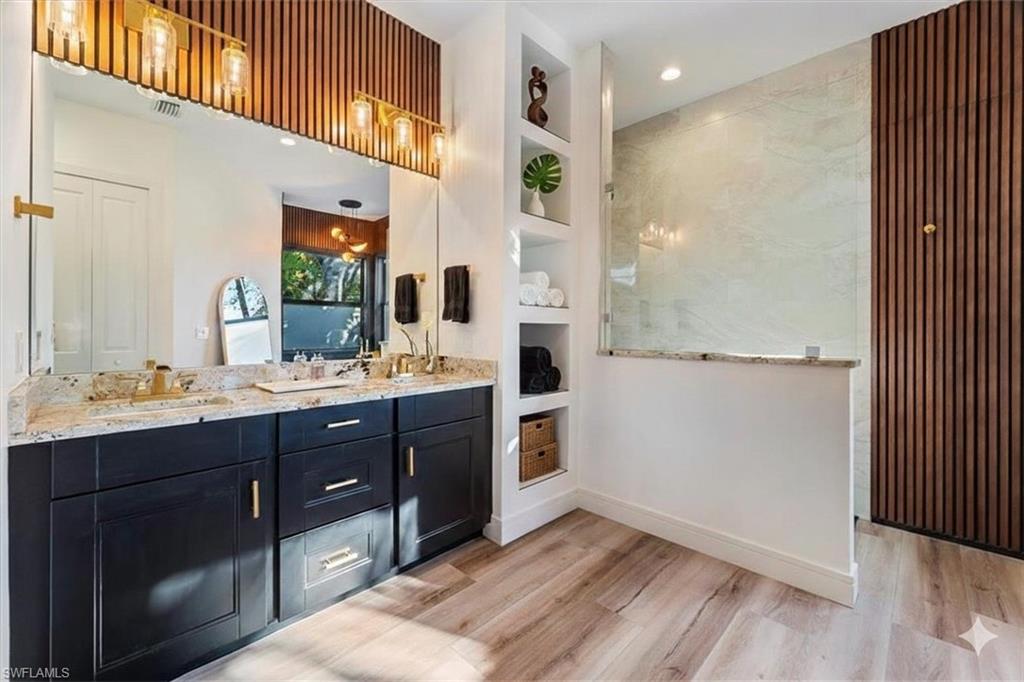 Full bath featuring built in features, double vanity, light wood-style floors, recessed lighting, and walk in shower