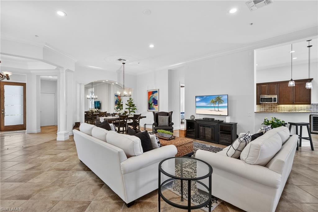 Living area with ornamental molding, a chandelier, ornate columns, wine cooler, and recessed lighting