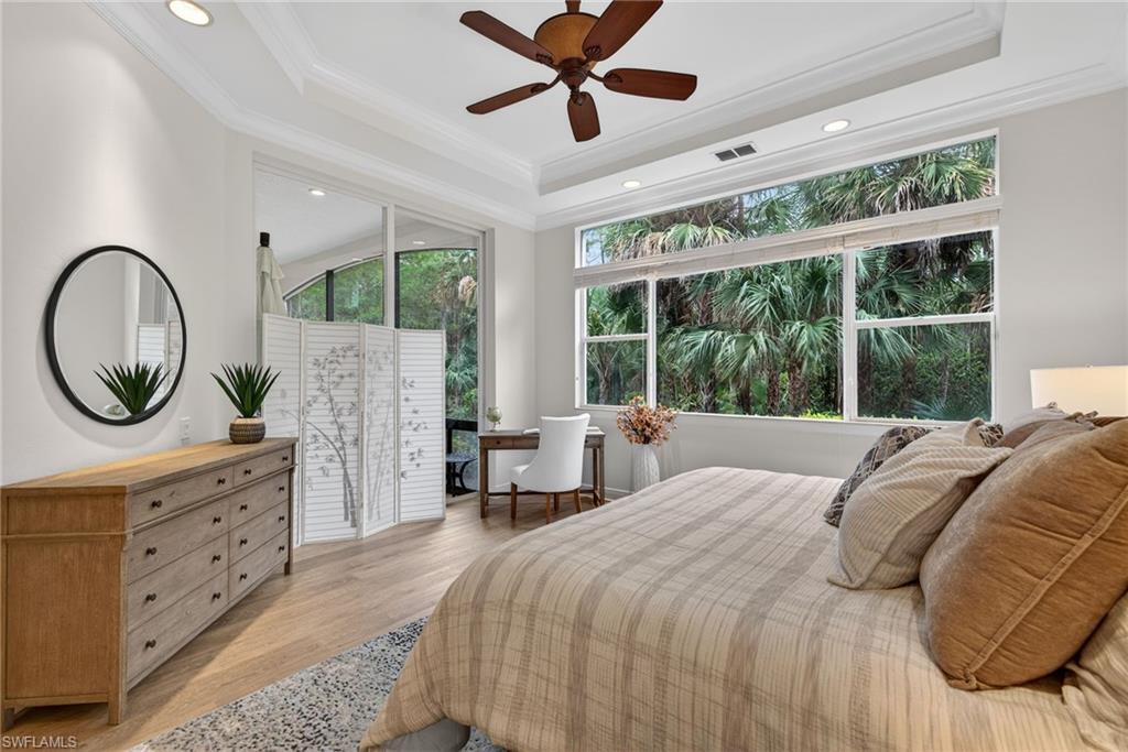 Bedroom featuring light wood-style flooring, ceiling fan, recessed lighting, ornamental molding, and a tray ceiling
