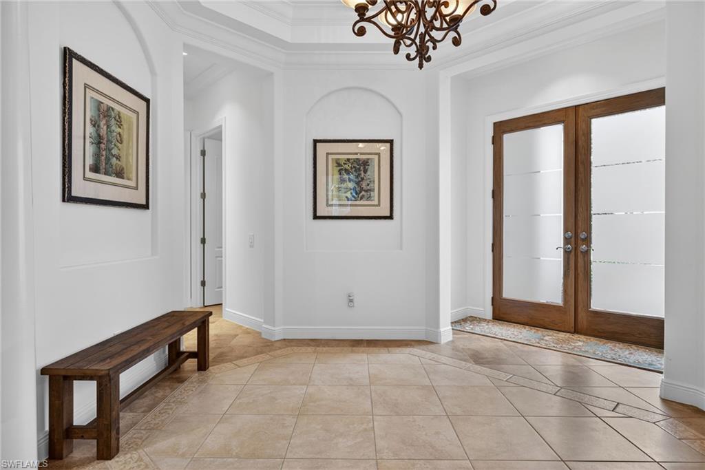 Entryway with french doors, crown molding, light tile patterned floors, and inlaid floor details