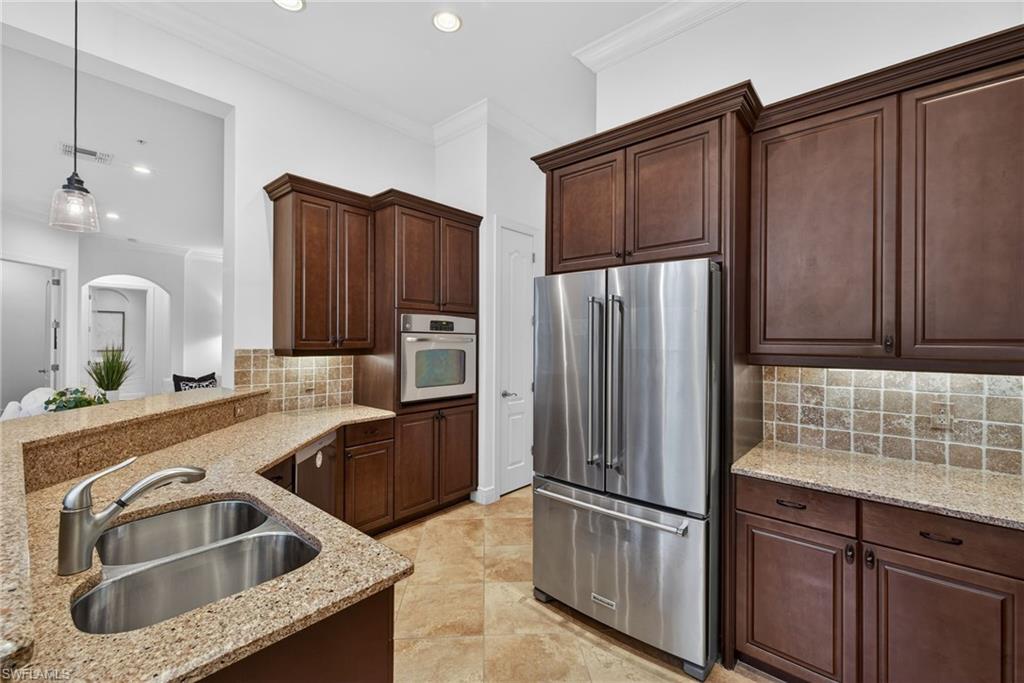 Kitchen featuring decorative backsplash, stainless steel appliances, decorative light fixtures, dark brown cabinets, and ornamental molding
