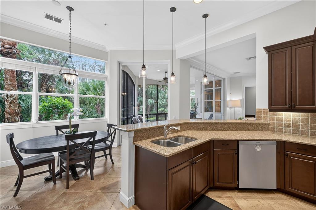 Kitchen with dark brown cabinetry, light stone countertops, decorative light fixtures, stainless steel dishwasher, and decorative backsplash