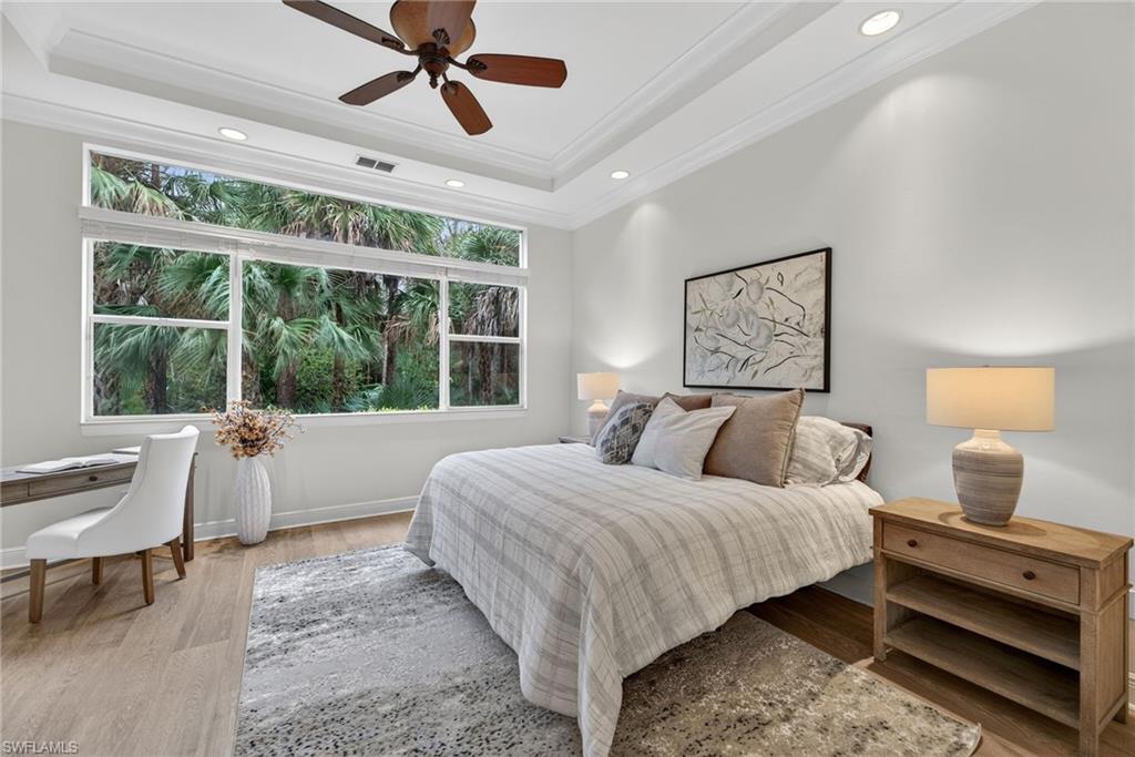 Bedroom with light wood-style flooring, ceiling fan, crown molding, recessed lighting, and a tray ceiling