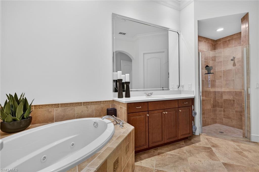 Full bathroom featuring ornamental molding, vanity, a stall shower, and a jetted tub