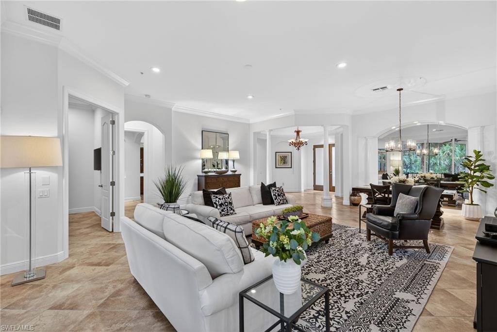 Living room with arched walkways, decorative columns, a chandelier, recessed lighting, and ornamental molding