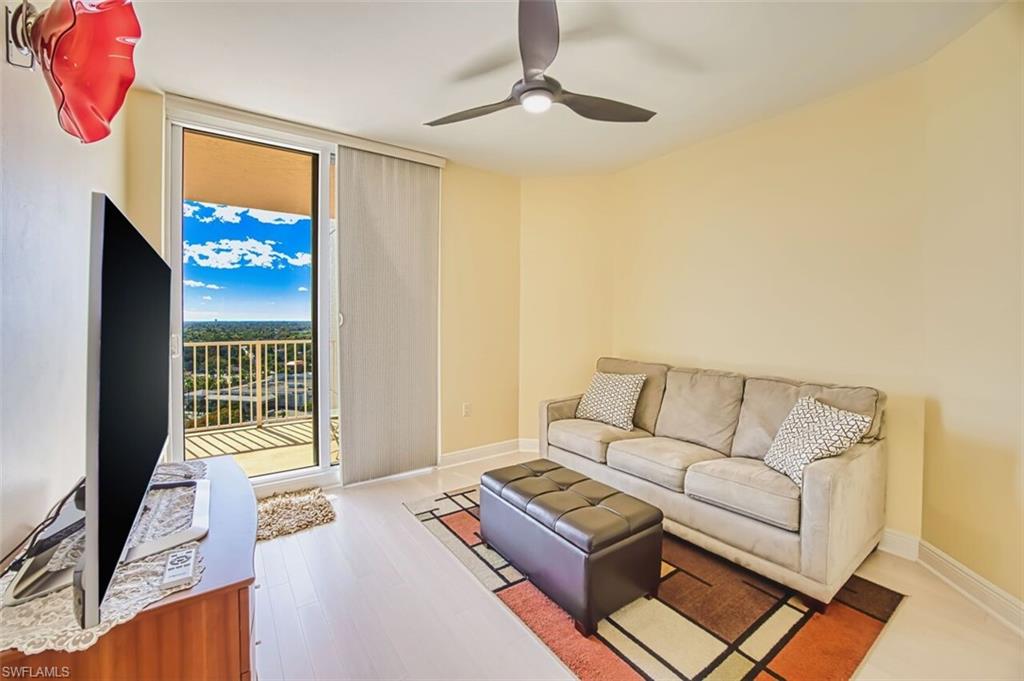 Living area with expansive windows, wood finished floors, and ceiling fan