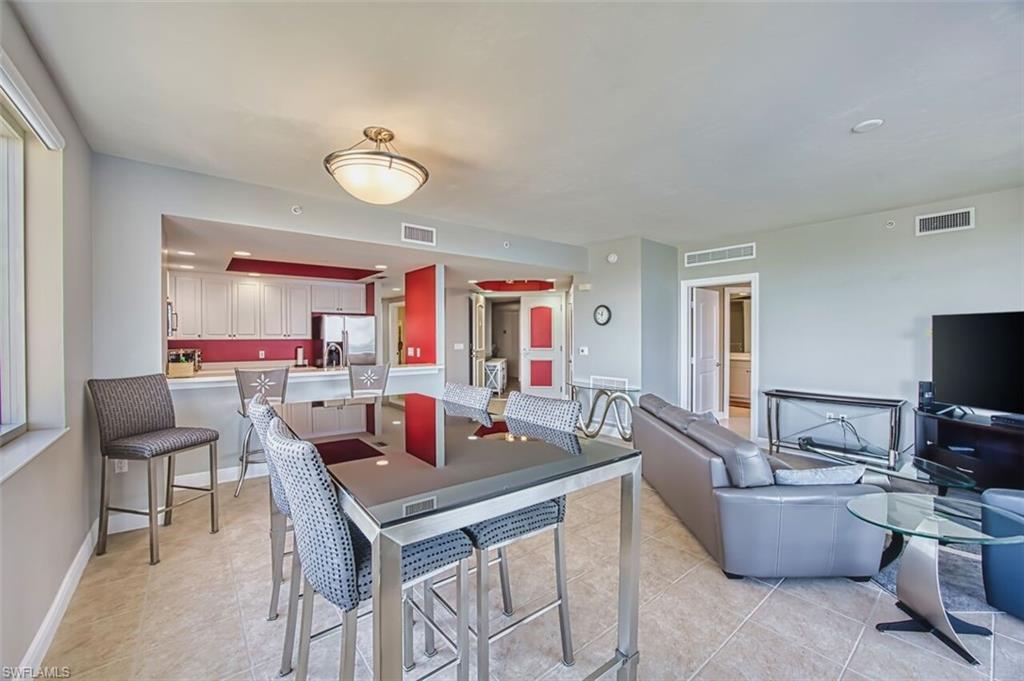 Kitchen with stainless steel fridge, light countertops, light tile patterned flooring, and a peninsula