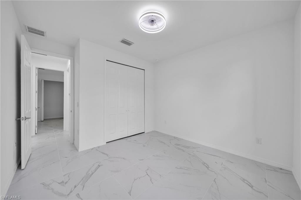 Unfurnished bedroom with light marble finish flooring and a closet
