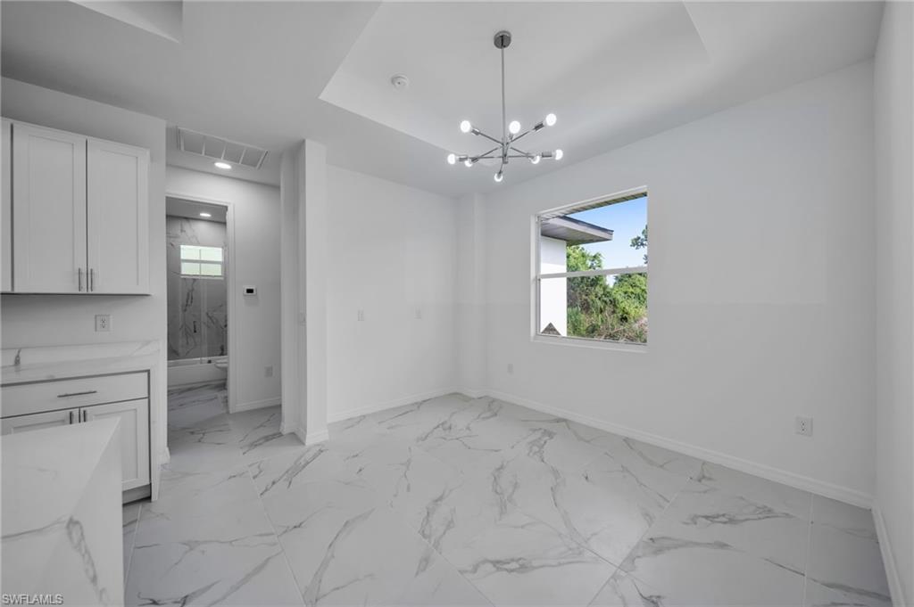 Unfurnished dining area with a chandelier and light marble finish floors