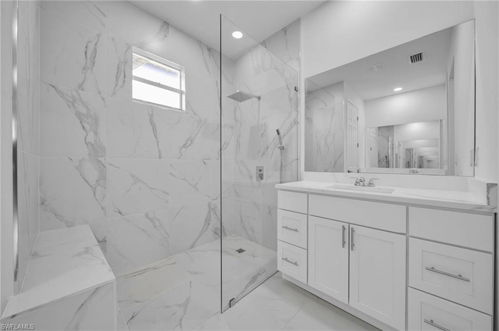 Bathroom with vanity, a marble finish shower, recessed lighting, and light marble finish floors